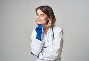 Porträt von ein Krankenschwester im Handschuhe und ein medizinisch Kleid auf ein Licht Hintergrund foto