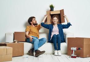 Mann und Frau sind Sitzung auf Sofa mit Kisten von Werkzeuge ziehen um Innere foto