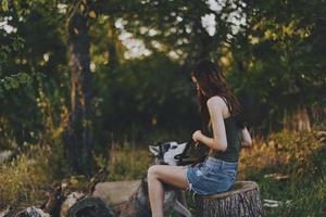 Frau und ihr heiser Hund glücklich spielen draußen im das Park unter das Bäume Lächeln mit Zähne im das Herbst gehen mit ihr Haustier foto