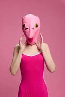 sehr seltsam Frau im ein Rosa Silikon Fisch Maske zum Halloween, verrückt Bild im Rosa Kleider foto