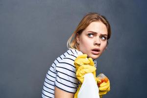 Reinigung Dame im gestreift T-Shirt Gummi Handschuhe abgeschnitten grau Hintergrund foto