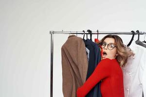 heiter Frau im ein rot Jacke in der Nähe von das Kleiderschrank Verkauf Licht Hintergrund foto