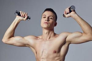 sportlich Mann mit Hanteln im Hände Übung Muskeln Stärke foto