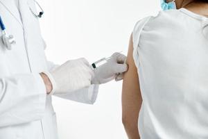 Arzt mit ein Spritze im Hand spritzen ein Impfstoff im schützend Handschuhe im ein Krankenhaus covid foto