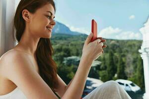 attraktiv jung Frau mit lange Haar auf ein öffnen Balkon Grün Natur Sommer- Tag Berg Aussicht foto