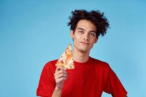 Kerl wo ist er und Haar im ein rot T-Shirt mit ein Scheibe von Pizza auf ein Blau Hintergrund foto