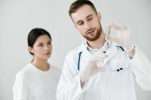 Arzt mit ein Spritze im Hand und Impfstoff im ein Ampulle geduldig im das Hintergrund foto