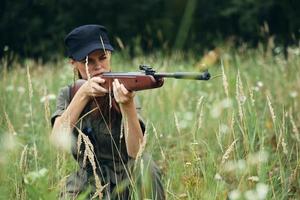 Frau Soldat mit ein Waffe im Abdeckung, ein schwarz Deckel Jagd Waffen Grün foto