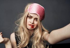 ein betrunken blond mit ein Rosa Schlaf Maske auf ihr Kopf Abstriche Lippenstift auf ihr Gesicht foto