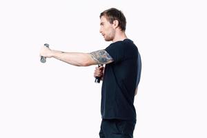 stark Mann Athlet im ein schwarz T-Shirt tun Übungen mit Hanteln im seine Hände Fitness foto