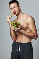 Sport Kerl mit ein nackt Torso Teller von Gemüse Salat isoliert Hintergrund foto