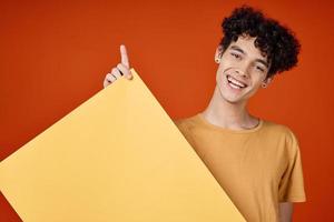 Kerl mit lockig Haar Gelb Poster im Hände Studio Werbung Kopieren Raum foto