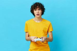 lockig Kerl Gelb T-Shirt mit Joystick Video Spiele Blau Hintergrund foto