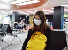 müde Frau im medizinisch Maske Gepäck Flughafen warten zum Flug foto