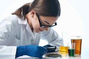 weiblich Labor Assistent suchen durch ein Lupe Biologie nachverfolgen chemisch Lösung foto