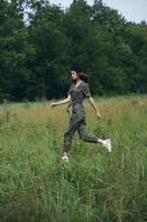 Frau im das Feld läuft auf das Gras im ein Grün Overall foto