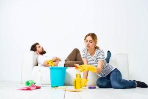 das Mann Lügen auf das Sofa Frau wäscht das Böden Bereitstellung Dienstleistungen Innere Hausarbeit foto