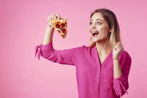 heiter blond mit Pizza im ihr Hände Müll Essen Snack Rosa Hintergrund foto