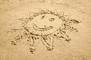 Sonne gestalten mit ein Lächeln gezeichnet auf Sand foto