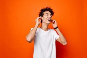 süß Kerl mit lockig Haar Weiß T-Shirt abgeschnitten Aussicht Orange Hintergrund foto