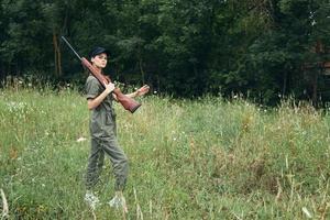 Militär- Frau Jagd im das Feld mit ein Waffe auf seine Schulter schwarz Deckel foto