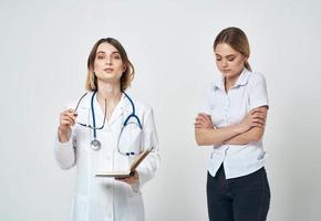 Krankenschwester mit Unterlagen im Hände und Frau geduldig auf ein Licht Hintergrund foto