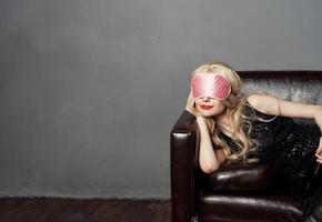 ein Frau mit ein Rosa Schlaf Maske Lügen auf das Couch mit ein Flasche von Bier im ihr Hand foto