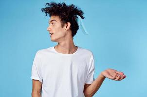 ein Mann im ein Weiß T-Shirt lockig Haar stecken Kamm Emotionen foto