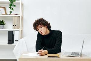 Mann Sitzung auf das Couch beim das Tabelle im Vorderseite von ein Laptop Lebensstil Technologie foto