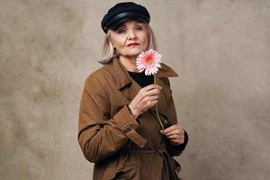 elegant Alten Frau im Mantel halten ein Blume Mode foto