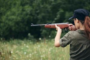 Frau Soldat mit ein Gewehr im Hand Ziel zurück Aussicht schwarz Deckel foto