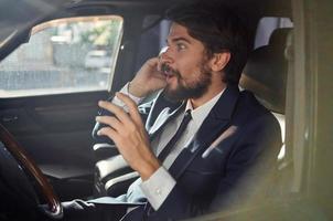 bärtig Mann Fahren ein Auto Ausflug Luxus Lebensstil Kommunikation durch Telefon foto