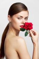 Frau mit lange mit ein Rose in der Nähe von das Gesicht zum Frisur Lippenstift foto