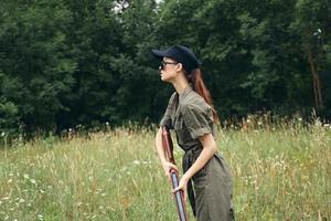 Frau auf Natur im ein Grün Overall Jagd Waffe frisch Luft foto