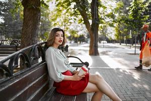 Frau im rot Rock im das Park auf das Bank draußen foto