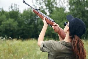Frau auf Natur halten ein Gewehr oben Jagd zurück Aussicht schwarz Deckel foto