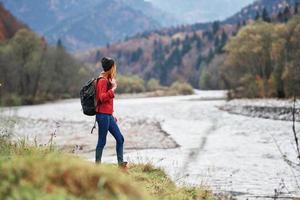 jung Frau mit Rucksack im das Berge Herbst Reise Tourismus Landschaft flach Wasser Fluss foto