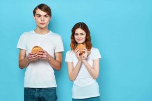 jung Paar mit Hamburger im ihr Hände schnell Essen Snack Müll Essen foto