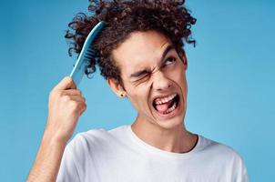 Probleme mit Kämmen Haar jung Kerl im T-Shirt und Kämmen Locken Modell- foto