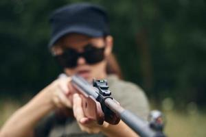 Frau auf Natur Frau mit ein Gewehr im Sonnenbrille Sicht Grün Overall foto