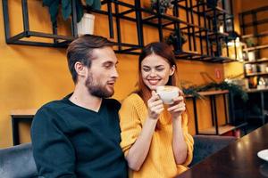 ein Frau im Liebe mit ein Tasse von Kaffee und ein glücklich Mann beim ein Tabelle im ein Cafe Innere freunde Kommunikation foto