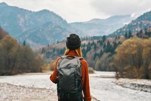 Frau Wanderer mit ein Rucksack sich ausruhen im das Berge im Natur in der Nähe von das Fluss foto