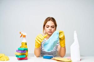 Reinigung Dame Sitzung beim das Tabelle Waschen liefert Arbeit Paletten Licht Hintergrund foto