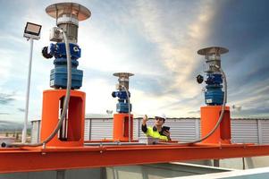 industriell Installation, überarbeitet Ingenieur tragen schützend Kleidung und Helm auf Kopf während Stehen im industriell Pflanze inspizieren Wasser liefern System foto