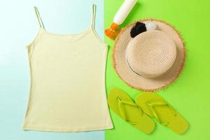 Sommer- Zubehör mit T-Shirt, Muscheln, Sonnenschutz Flasche und Stroh Hut auf Blau und Grün Hintergrund oben Aussicht eben legen foto