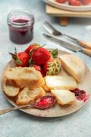 Frühstücksteller mit Käse, Brot, Erdbeeren und Marmelade, Nahaufnahme foto