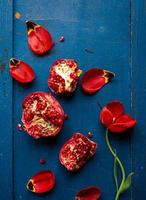 rote Tulpe und Granatapfel mit Samen auf dunkelblauem hölzernem Hintergrund, flache Anordnung foto