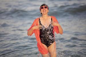 glücklich Frau beim das Meer mit spritzt foto