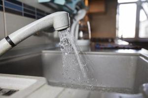 Wasser ist Gießen von ein Wasserhahn. Wasser Zapfhahn auf das Hintergrund von das Küche. Haus Wasser Verbrauch. foto