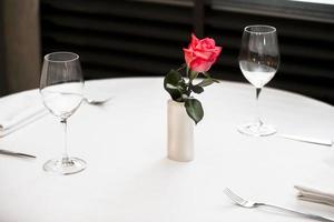 Weiß Tabelle mit Brille und Besteck. leeren Restaurant Tabelle mit rot Rose. foto
